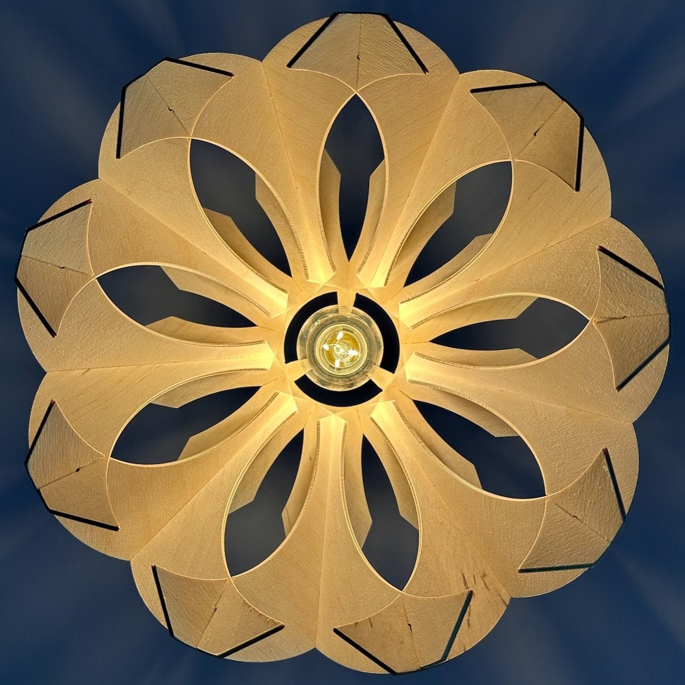 Bottom view of a wooden pendant lamp with a flower-like design, showcasing intricate craftsmanship in eco-friendly birch wood