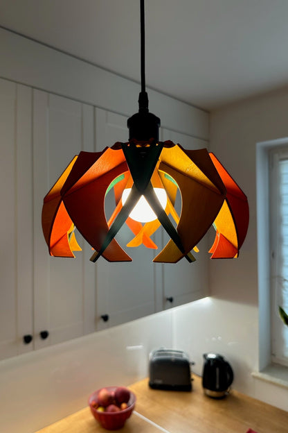 Small colorful pendant lamp in a kitchen setting, featuring a vibrant mix of green, yellow ochre, and scarlet stain. The lamp&#39;s petal-like wooden ribs create a dynamic and playful ambiance, with the light filtering through the vibrant colors.